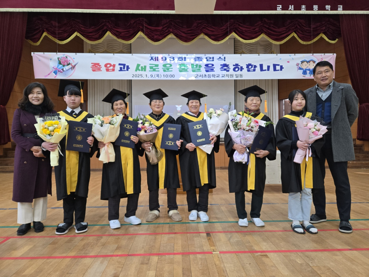군서초등학교 졸업식에서 늦깎이 할머니 졸업생들(왼쪽부터 이선숙, 김순덕, 장화녀, 박향임) 어르신과 어린 학생들(좌측 김민건, 우측 김산들), 손향미 교장선생님(맨 좌측), 박정조 담임선생님(맨 우측)이 기념촬영을 하고 있다. 사진 제공 / 군서초등학교